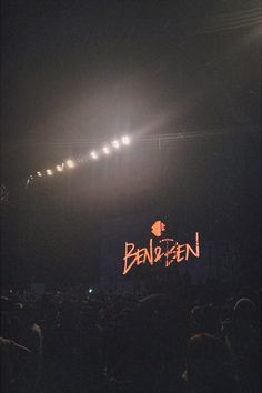 an audience at a concert with the word bennien lit up in the background