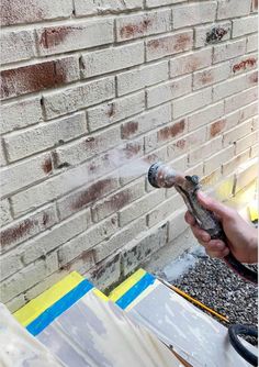 a person spraying cement on a brick wall with a sprayer in front of them