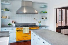 a kitchen with yellow and white cabinets, stainless steel appliances and wood flooring is shown