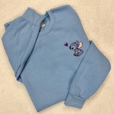 "Stitch with a heart design embroidered on a crewneck sweatshirt. The sweatshirt is a soft spun crewneck and is very soft cotton poly blend, which is so comfy. Design is embroidered as shown It takes 1-2 weeks to make and process orders for shipping. If you require it sooner, you will need to purchase the \"rush order add-on\" Item Description: Unisex Men Sizing Cotton and Polyester Pull On Long Sleeve Crewneck No returns or exchanges on custom items. Please contact me with any concerns on your Cute Crew Neck Sweater With Ribbed Cuffs, Cute Crew Neck Top With Ribbed Cuffs, Cute Crew Neck Sweatshirt With Ribbed Cuffs, Blue Embroidered Fleece Sweatshirt, Cute Embroidered Sweatshirt For Loungewear, Cute Crew Neck Embroidered Sweatshirt, Cute Crew Neck Sweater With Embroidered Logo, Cute Crew Neck Sweatshirt With Embroidered Logo, Cute Cotton Sweater With Embroidered Logo