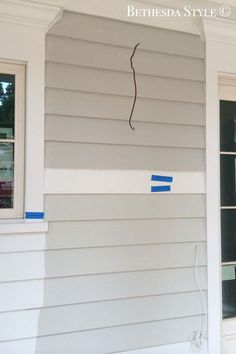 a house that has been painted white with blue tape on the siding and window trim