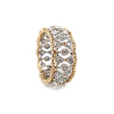 a gold and silver ring with two rows of diamonds on the inside, set against a white background