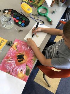 a young boy sitting at a table working on an art project