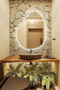 a bathroom with stone walls and a round mirror above the sink, along with palm trees