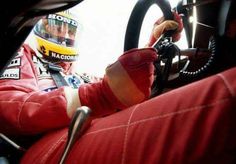 a man sitting in the driver's seat of a race car with his hand on the steering wheel