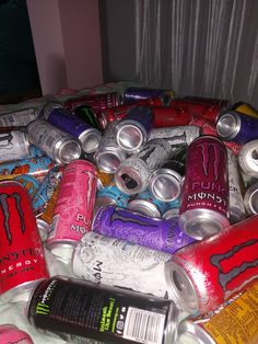 many cans of soda are stacked on top of each other in the middle of a bed