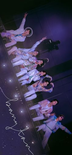 group of young men standing on stage in white outfits