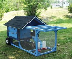 a small blue chicken coop in the grass