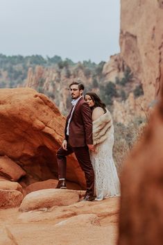 a man and woman standing on rocks in the desert