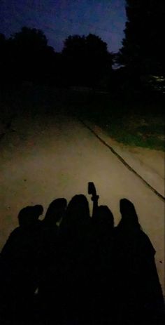 four people sitting on the ground at night with their cell phones in their hands,