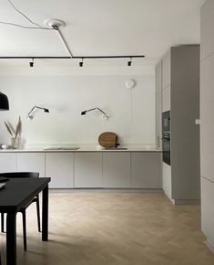 an empty kitchen with white walls and wooden flooring is pictured in this image, there are lights hanging from the ceiling