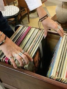 two hands reaching into a drawer full of records in a room filled with tables and chairs