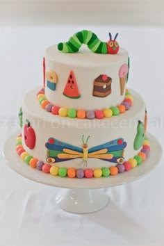 a three tiered cake decorated with colorful candies and fondant caterpillars