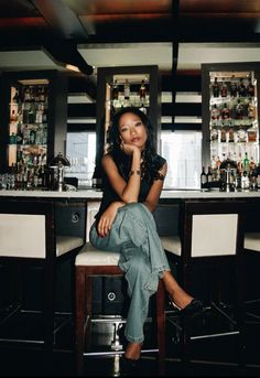 a woman sitting on a stool in front of a bar