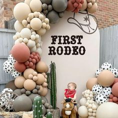 a child on a toy horse in front of a balloon arch