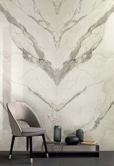 a chair and table with vases on it in front of a marbled wall