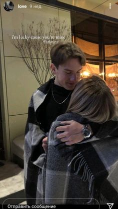 two people embracing each other in front of a building