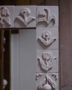 several white flowers are placed on the wall in front of a mirror, which is being made out of clay