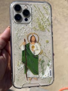 a person holding up a phone case with an image of jesus painted on the back