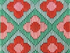 a close up view of an embroidered material with red and green flowers on the side