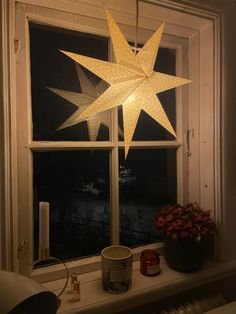 a lighted star hanging over a window sill