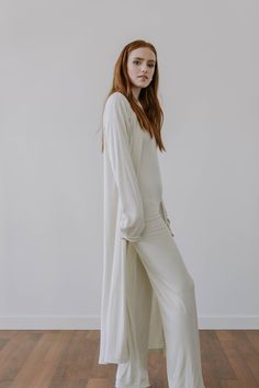 "This luxe, full length lightweight cardigan is made from a finely ribbed fabric with a super soft hand feel. It has a relaxed fit, drop shoulders and slouchy sleeves for a slightly oversized look. Made from 90% plant based, environmentally responsible TENCEL, it's light as air while providing the perfect amount of coverage. The 10% Spandex fabrication also adds a bounce and stretch for exceptional comfort. Like all of our pieces, this cardigan is exclusively handmade to order by us in limited q Cream Long Sleeve Loungewear Robe, Cream Long Sleeve Robe For Loungewear, Cream Open Front Cardigan For Daywear, Fitted Long Sleeve Solid Robe, Fitted Long Sleeve Solid Color Robe, Versatile Long Sleeve Cardigan For Loungewear, Cream Long Sleeve Cardigan For Loungewear, Long Sleeve Relaxed Fit Robe For Fall, Fitted Cream Cardigan For Loungewear