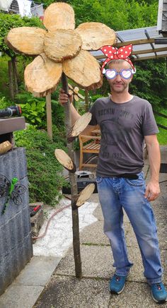 a man standing next to a wooden tree with a red bow on it's head