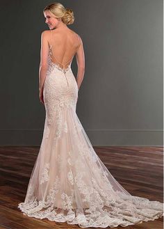 the back of a wedding dress with an open back and sheer lace on it, in front of a wooden floor