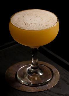 a drink sitting on top of a wooden table next to a black wall and floor