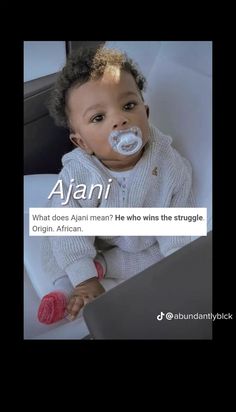 a baby with a pacifier in its mouth sitting next to a lap top computer