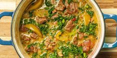 a blue pot filled with meat and vegetables on top of a wooden table next to a cutting board