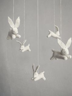 three white ceramic animals hanging from strings in the shape of birds and rabbits, on a gray background