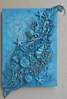 a blue piece of art with sea shells and starfishs on the bottom half