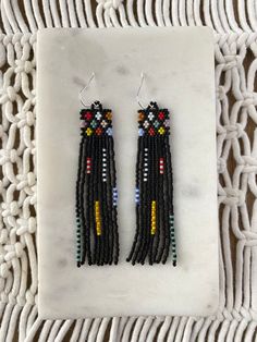 two pairs of beaded earrings with multicolored beads on a white marble surface