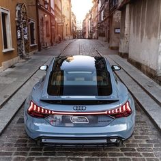 the rear end of an audi car parked on a cobblestone street with buildings in the background