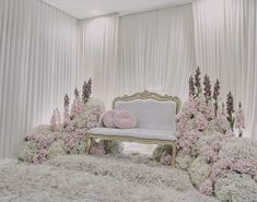 a white couch sitting on top of a carpet covered floor next to flowers and greenery