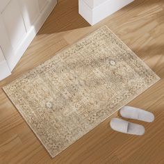 a pair of slippers sitting on top of a wooden floor next to a rug