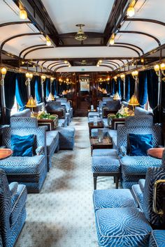 the inside of a train car with blue couches and chairs on it's sides