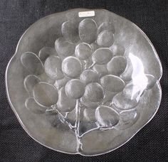 a silver plate with fruit on it sitting on a black tableclothed surface, in the shape of a flower