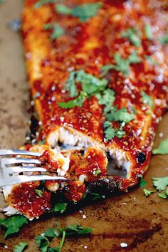 a piece of pizza with sauce and parsley on it being eaten by a fork