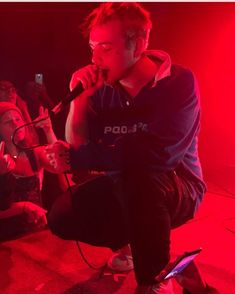 a man sitting on top of a stool while holding a microphone in his hand and singing into a mic