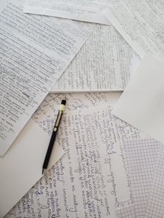 several pieces of paper with writing on them and a pen laying on top of it