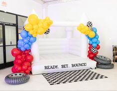 an inflatable balloon arch with checkered tires and balloons on the floor next to it