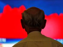 the back of a man's head in front of a red and blue television screen