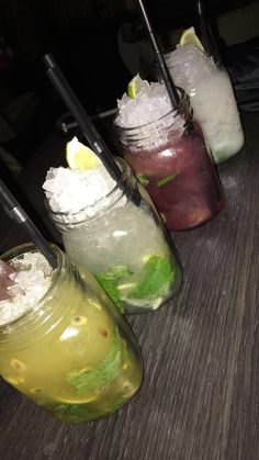 three mason jars filled with different types of drinks on top of a wooden table next to each other