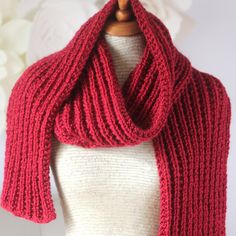 a red knitted scarf sitting on top of a mannequin