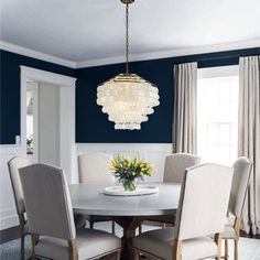 a dining room table with chairs and a chandelier hanging from it's ceiling