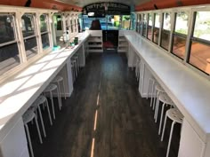 the inside of a bus with tables and chairs lined up on each side, along with lots of windows