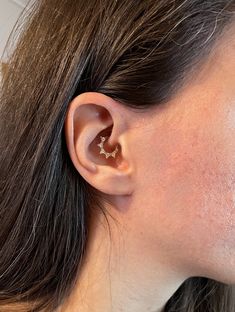 a close up of a person's ear wearing an ear cuff with stars on it