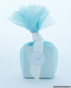 a blue box with a white ribbon tied to it's side and a tag on the top